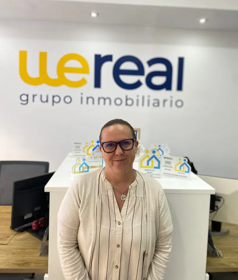 Retrato de Carolina Sánchez López, agente de Wereal en Alicante, frente al logotipo de la oficina